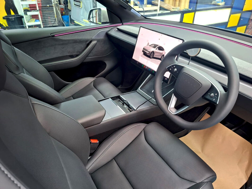 Reflections across the coated panels of the Tesla Model YL.