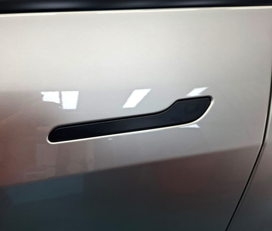 A coated door panel and flush handle on the Tesla Model YL, reflecting cleanly.