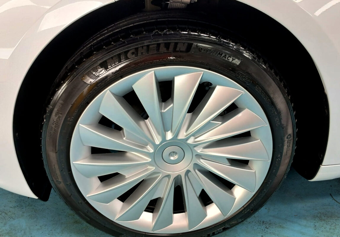 The coated bonnet of the Tesla Model 3 under workshop lighting.