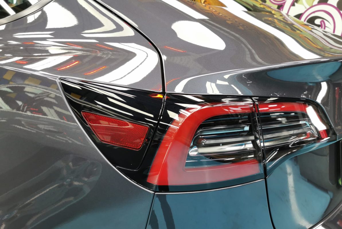 The coated bonnet of the Tesla Model 3 under workshop lighting.
