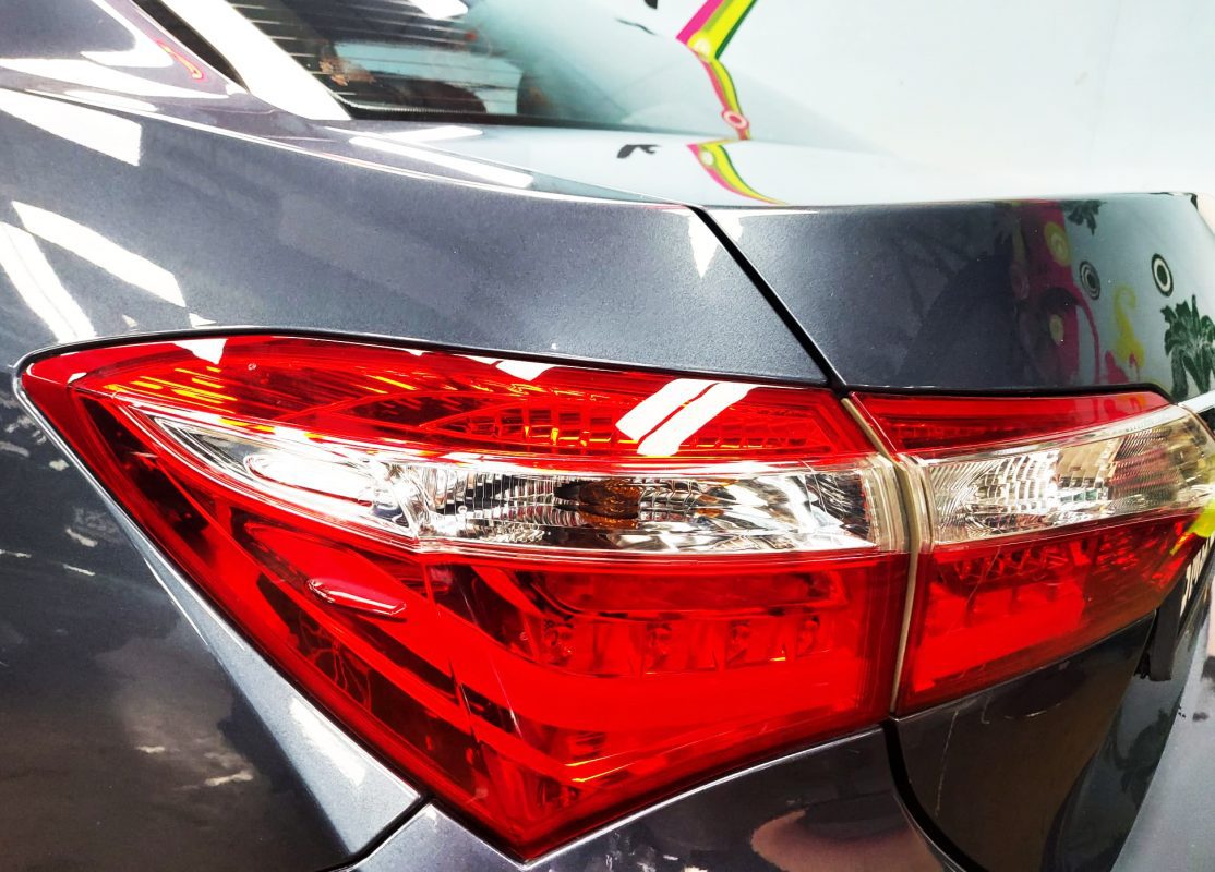 The coated bonnet of the Toyota Altis under workshop lighting.