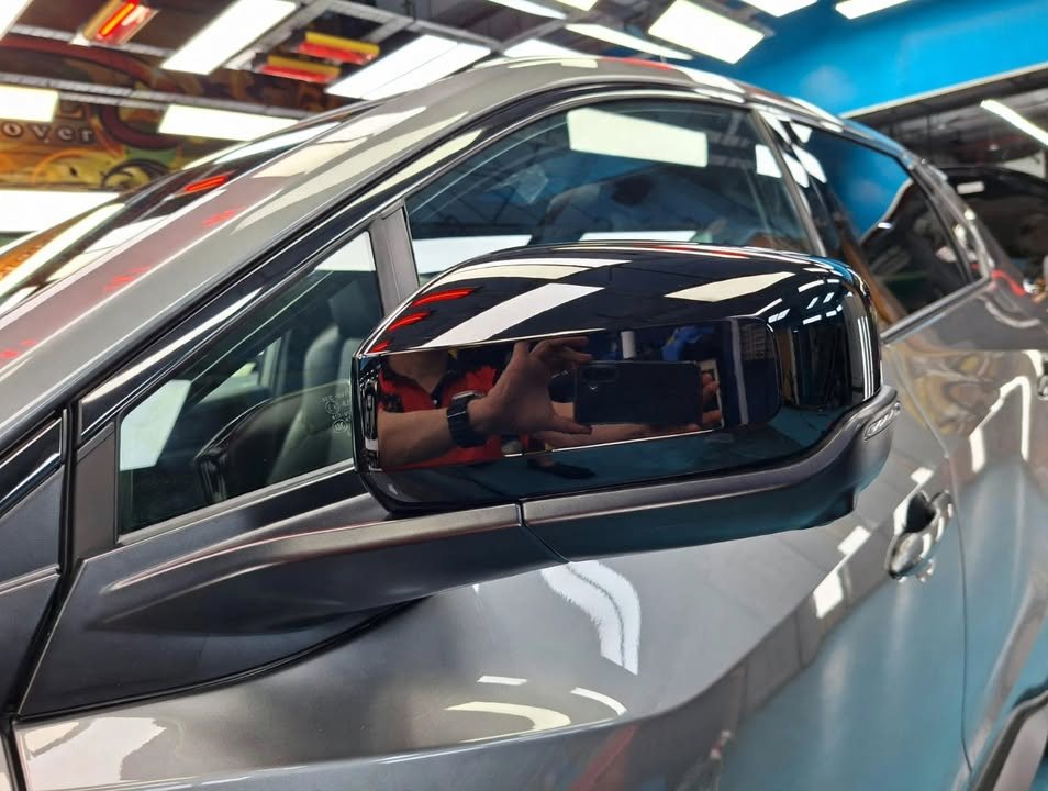 Gloss black wing mirror on the Toyota bZ4X reflecting the workshop.