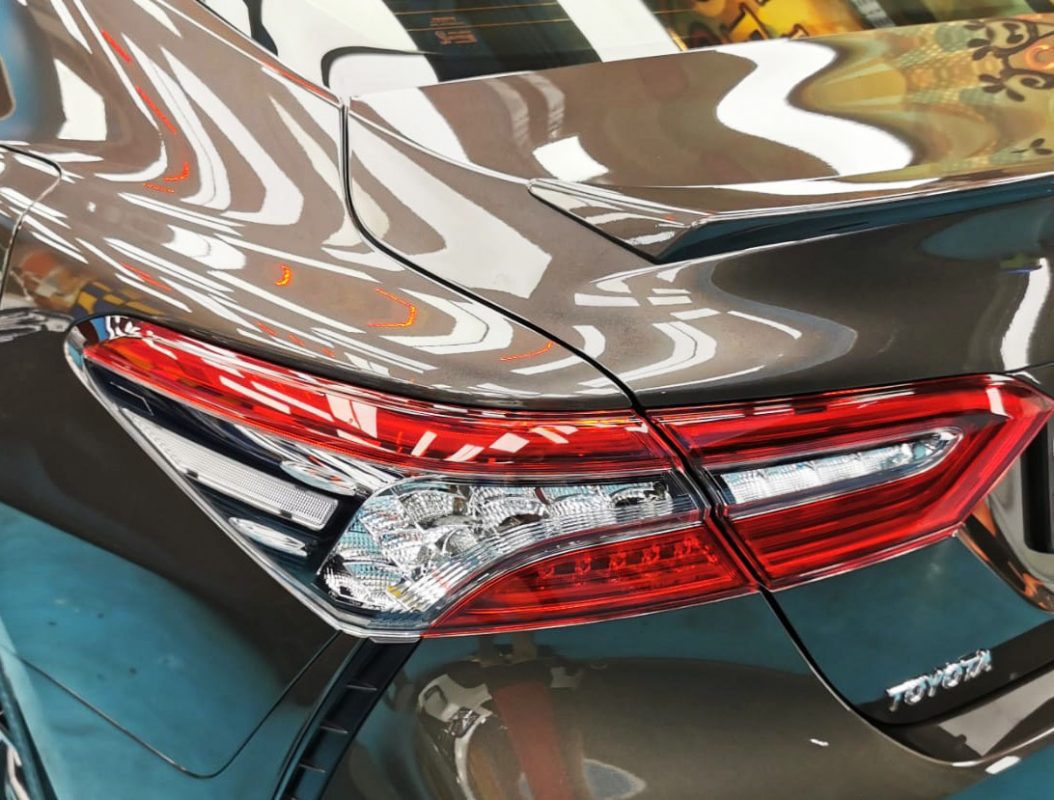 The coated bonnet of the Toyota Camry under workshop lighting.