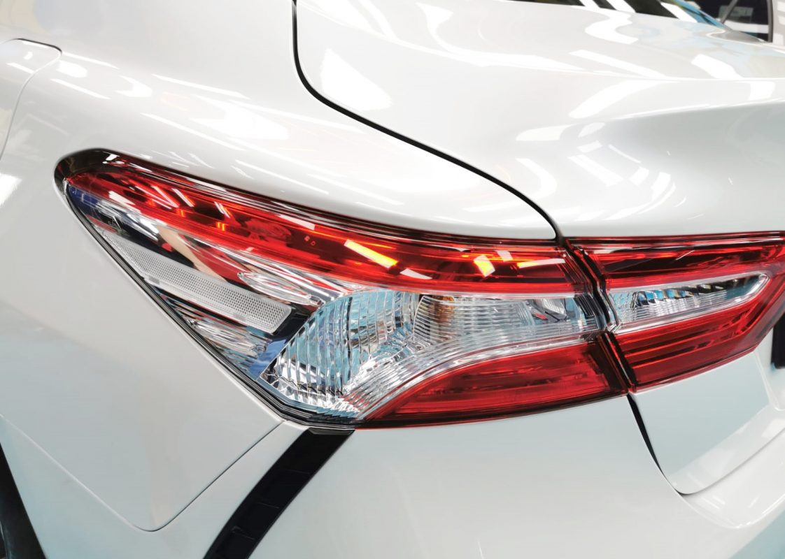 The coated bonnet of the Toyota Camry Hybrid under workshop lighting.