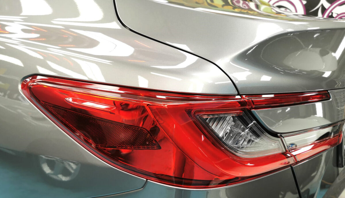 The coated bonnet of the Toyota Camry under workshop lighting.