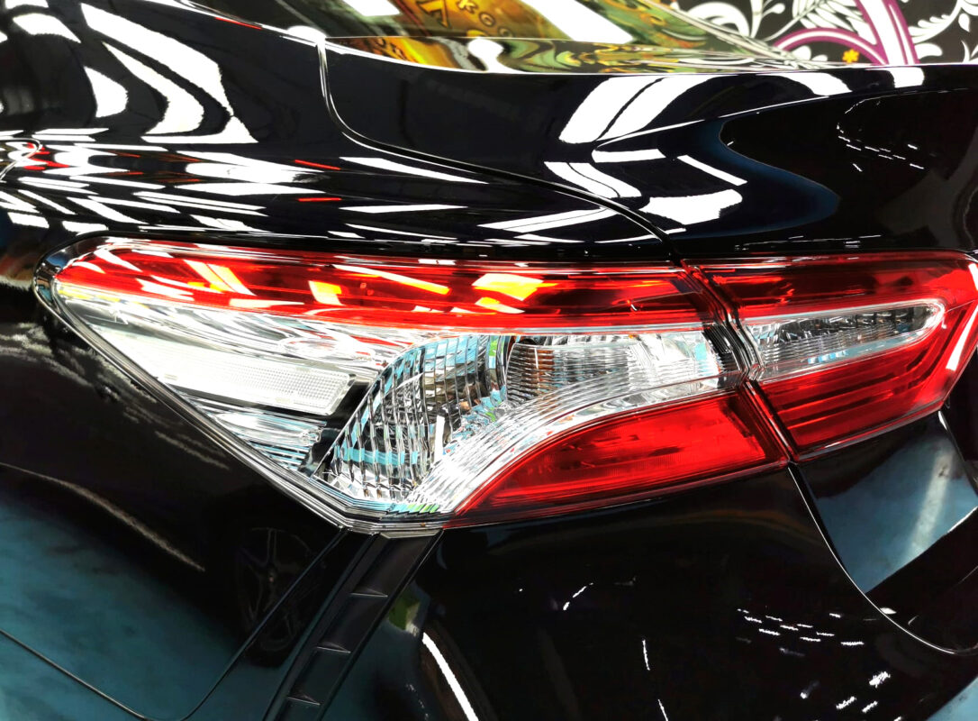 The coated bonnet of the Toyota Camry under workshop lighting.