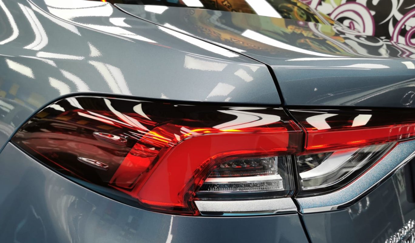 The coated bonnet of the Toyota Corolla Altis under workshop lighting.