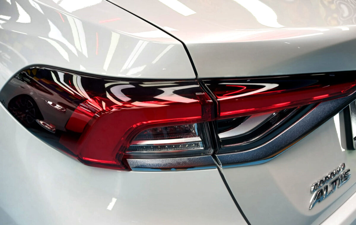 The coated bonnet of the Toyota Corolla Altis under workshop lighting.