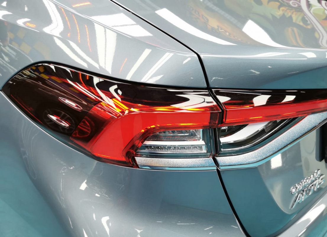 The coated bonnet of the Toyota Corolla Altis Elegance under workshop lighting.