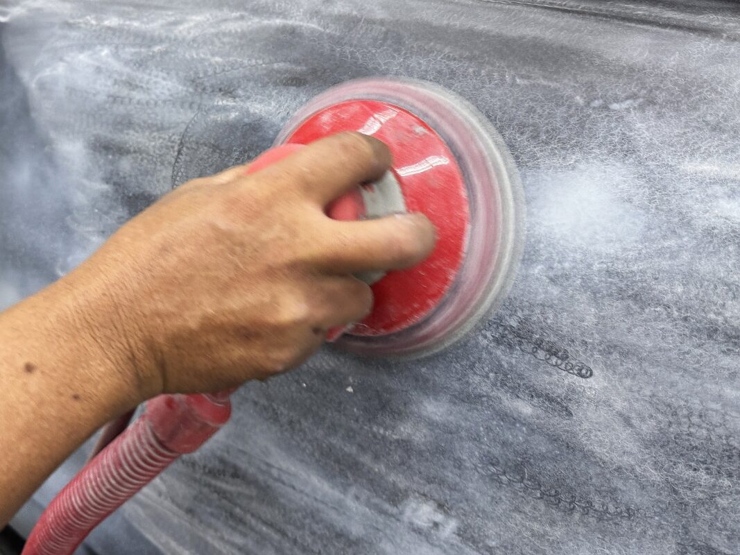 Machine-sanding a panel on the Corolla Altis to take the surface back.