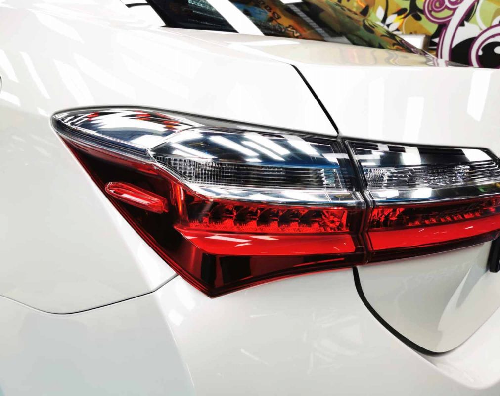 The coated bonnet of the Toyota Corolla Altis under workshop lighting.