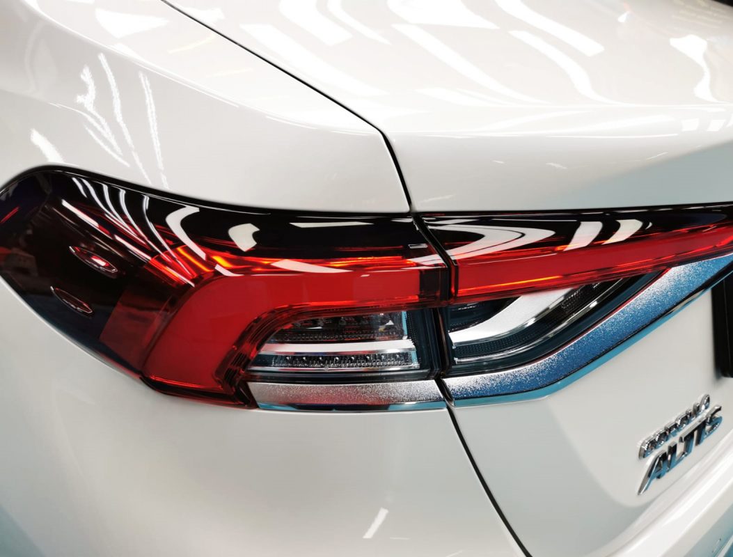 The coated bonnet of the Toyota Corolla Altis under workshop lighting.
