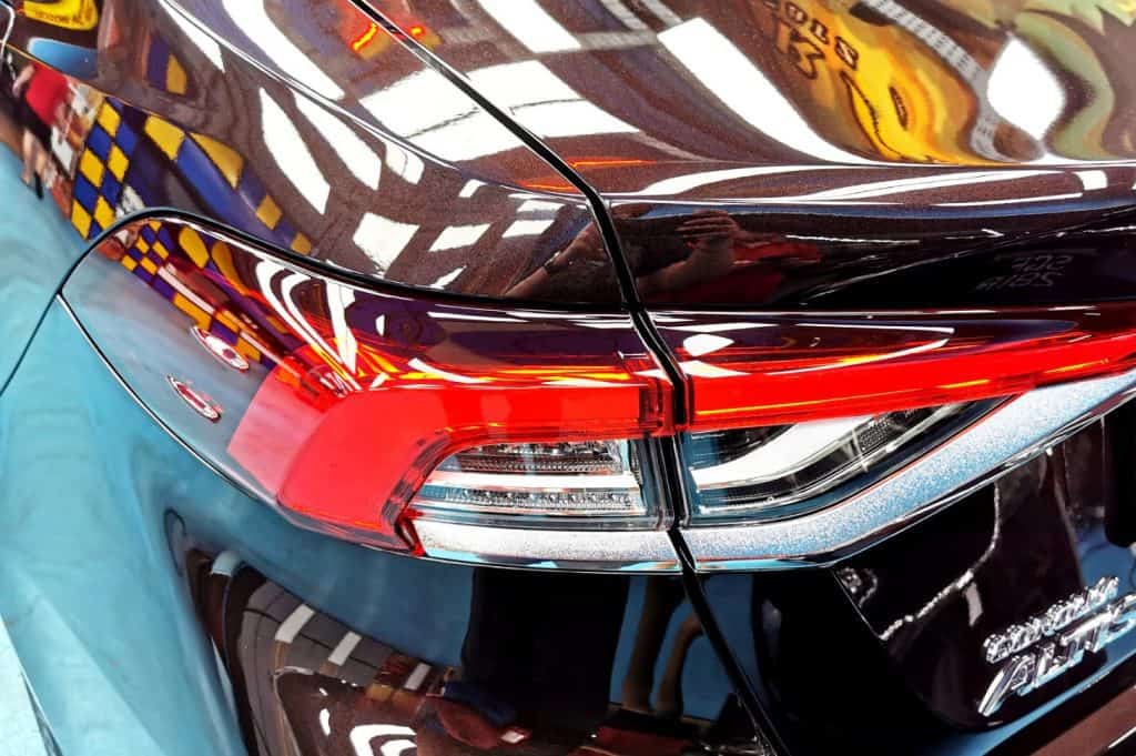 The coated bonnet of the Toyota Corolla Altis under workshop lighting.
