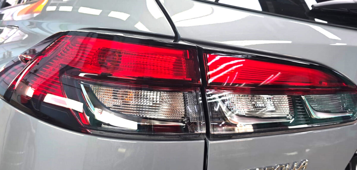 The coated bonnet of the Toyota Corolla Cross Hybrid under workshop lighting.