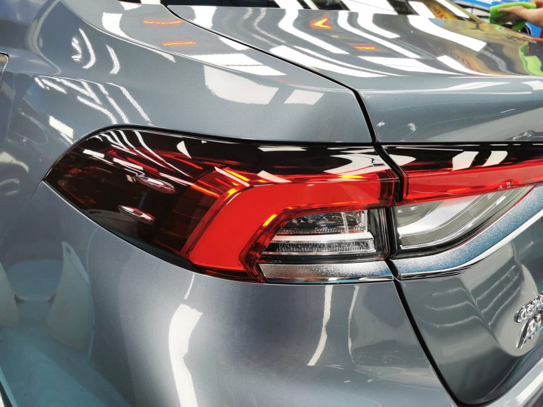The coated bonnet of the Toyota Corolla under workshop lighting.