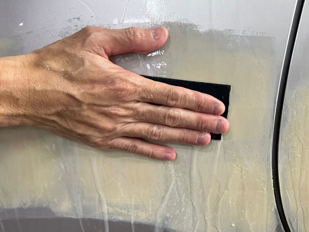 Wet-sanding the Estima to bring the whole surface smooth and level.