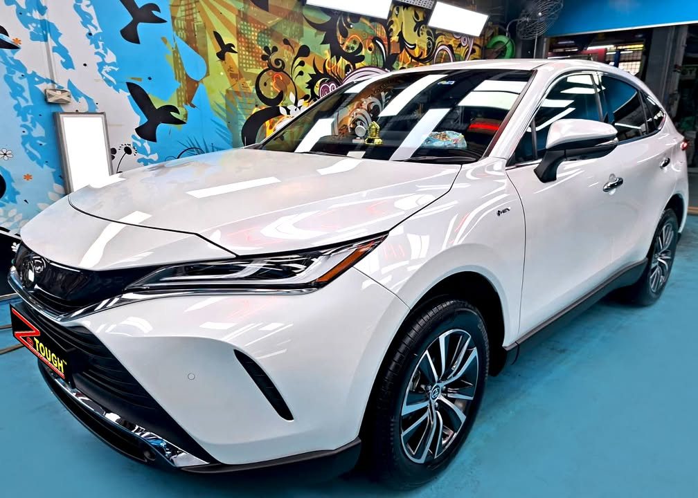 Front three-quarter view of a white Toyota Harrier in the Revol Carz hall after coating.