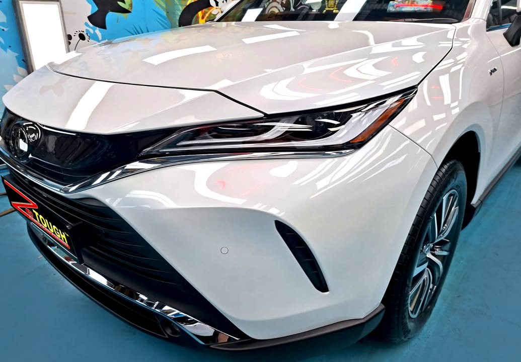 Front of the white Harrier showing the slim headlight and glossy bonnet.