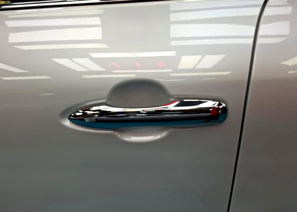 Chrome door handle on a white Harrier door panel.