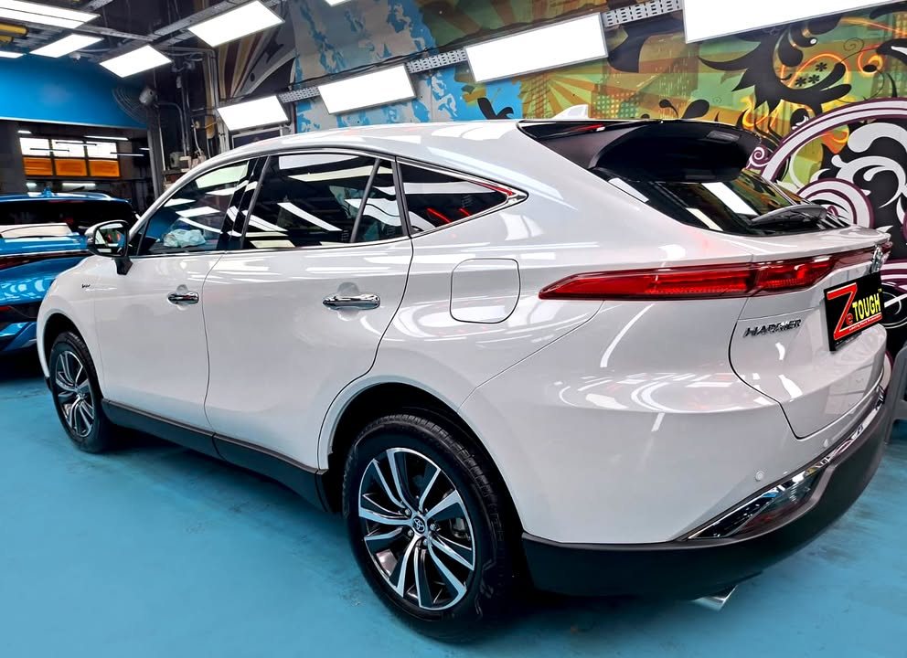 Rear three-quarter view of the white Toyota Harrier showing the tail light bar.