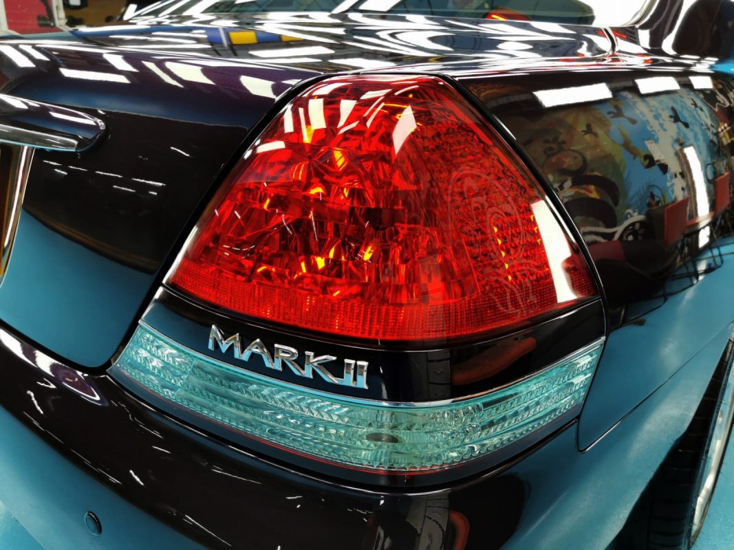 The coated bonnet of the Toyota Mark II under workshop lighting.