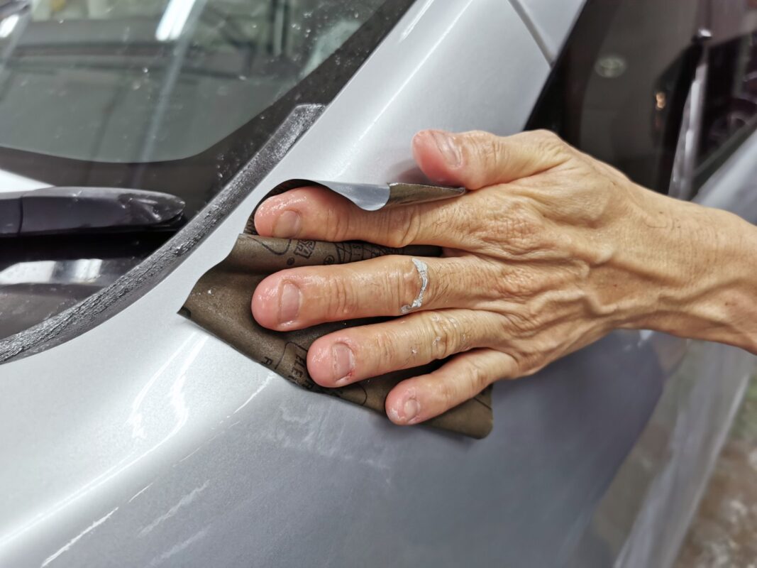 Wet-sanding the Toyota Noah's panels to achieve a smooth, even surface.