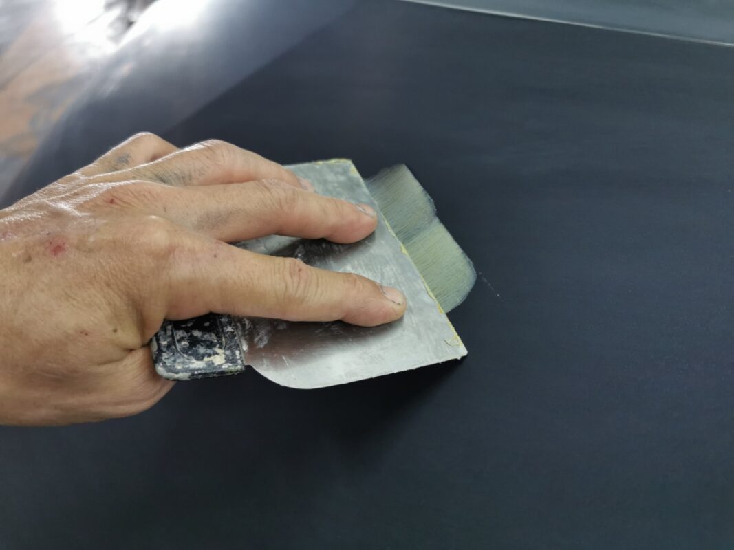 Sanding the repaired panels on the Toyota Previa Aeras to level the surface.
