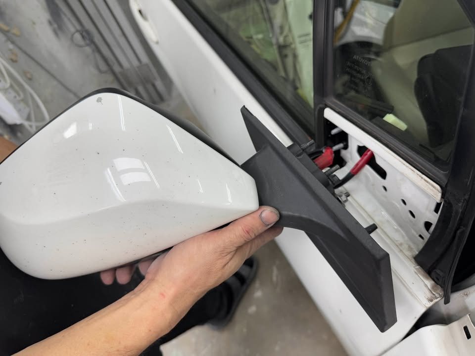 Side mirror being removed from the white door.