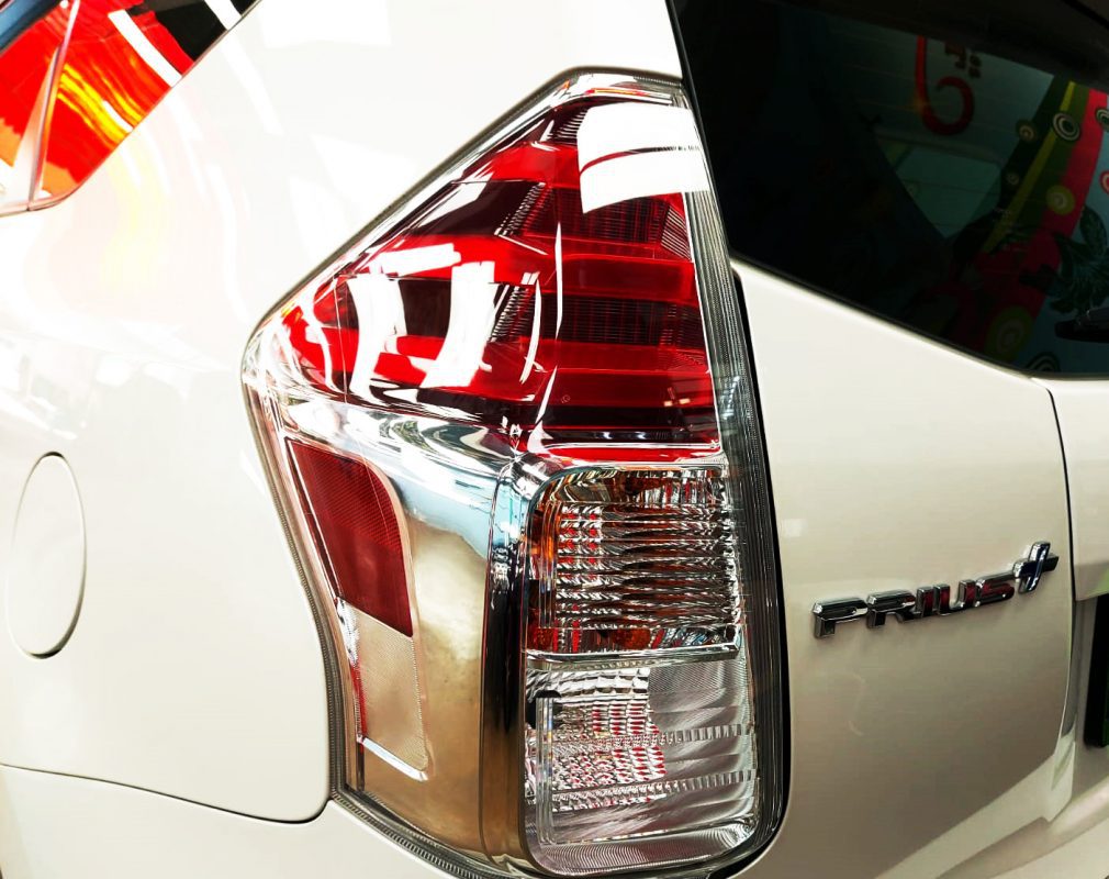 The coated bonnet of the Toyota Prius Plus under workshop lighting.