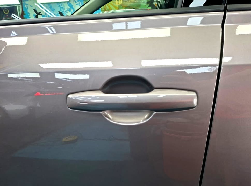 Bronze grey door panel and door handle with sharp reflections.