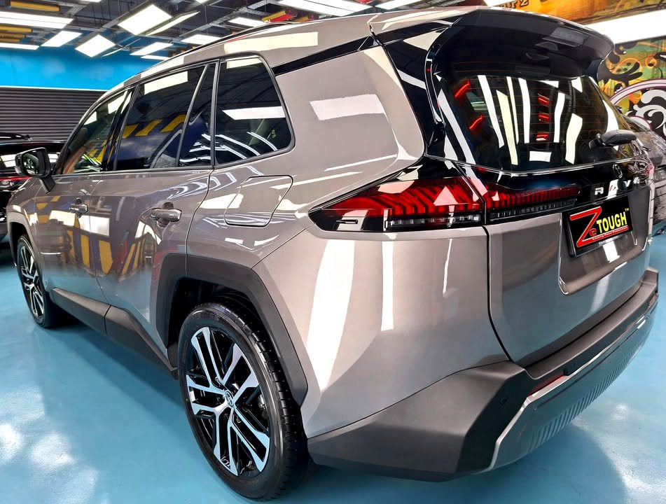 Bronze grey Toyota RAV4, rear three-quarter view, in the workshop.