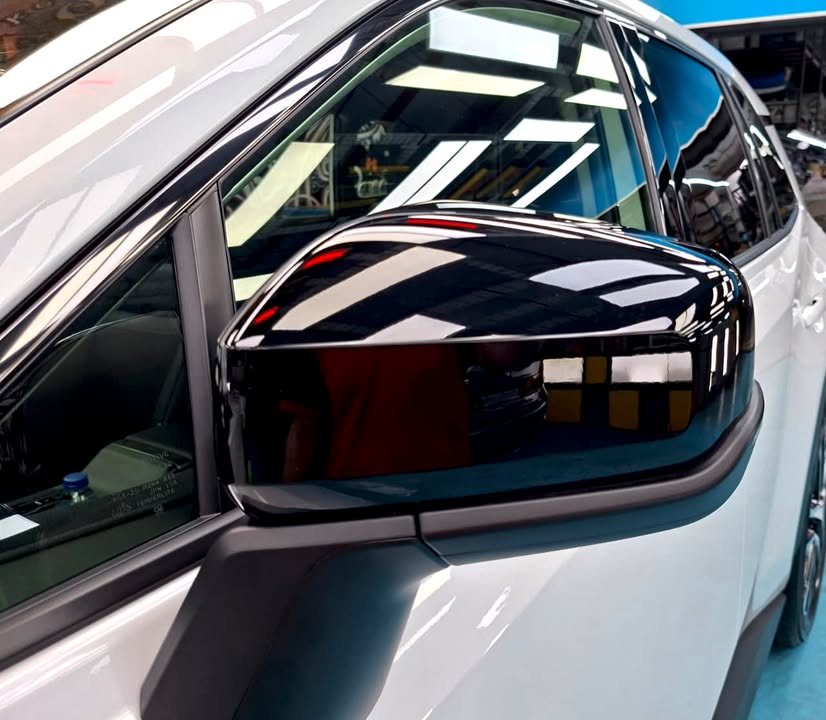 Gloss black side mirror cap reflecting the ceiling lights.