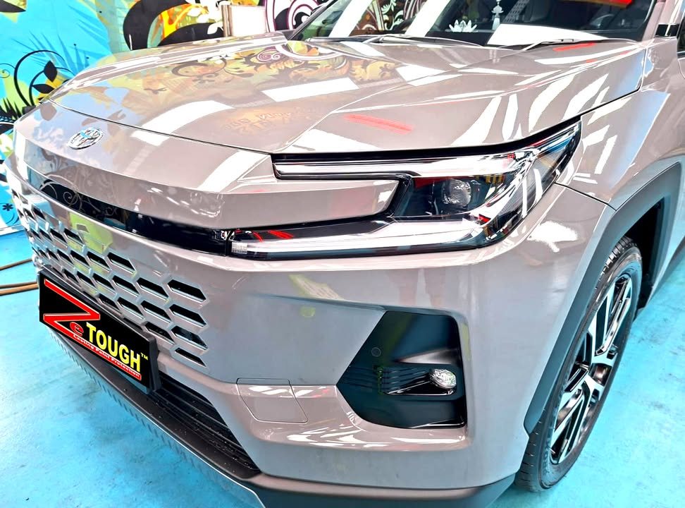 Front of the grey Toyota RAV4 showing the headlamp, grille and bonnet reflections.