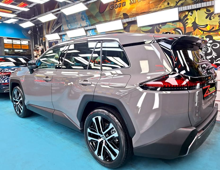 Rear three-quarter view of the grey Toyota RAV4 with black roof in the workshop.
