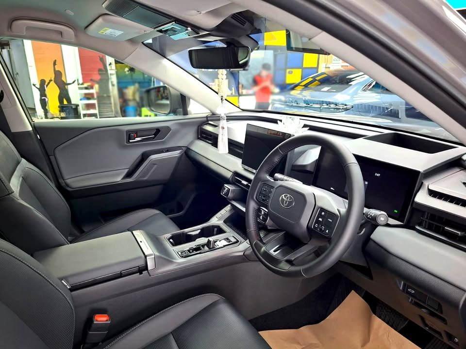 Toyota RAV4 cabin with dark seats, steering wheel and wide dashboard screen.