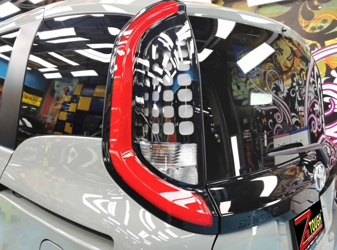 The coated bonnet of the Toyota Sienta Hybrid under workshop lighting.