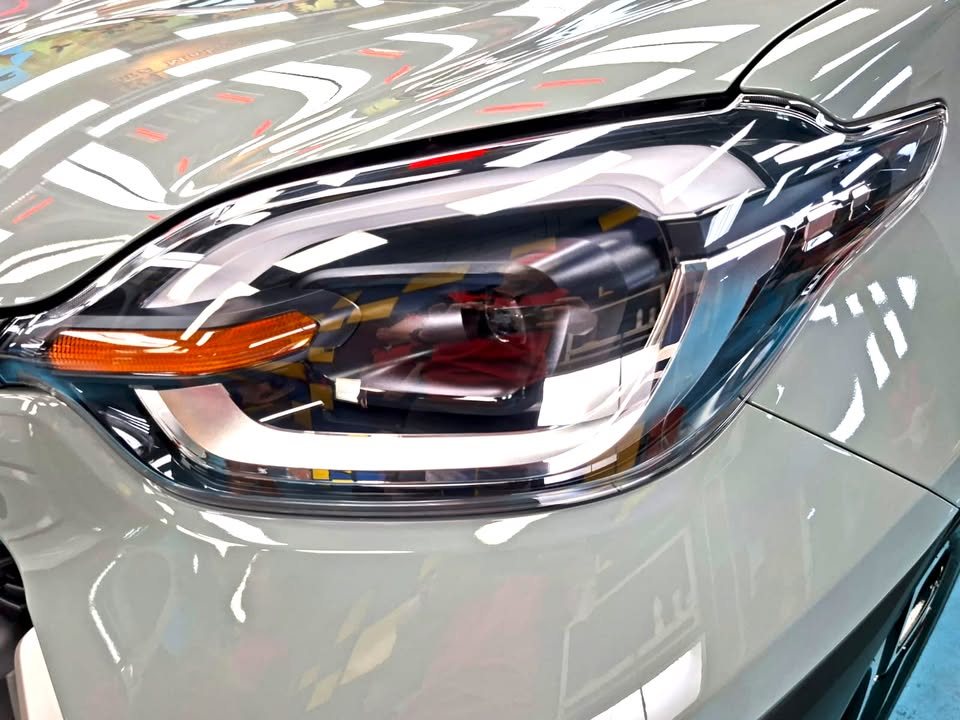 Close-up of the Sienta headlamp with ceiling lights reflected.