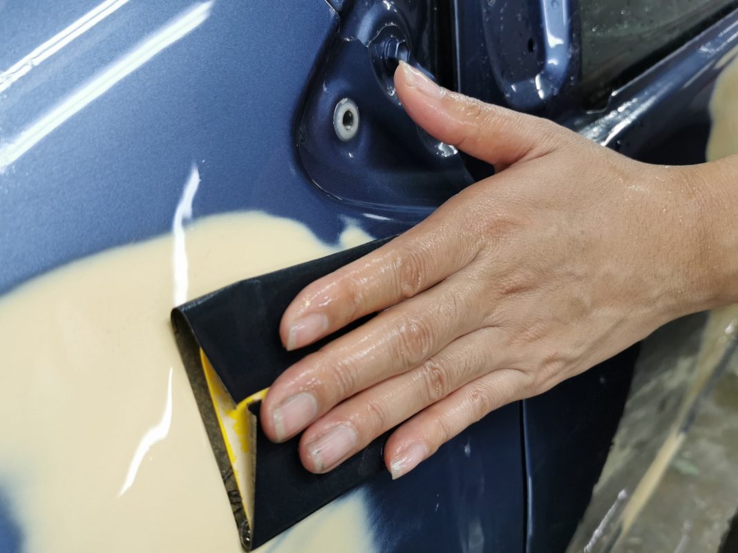 Wet-sanding the Vios's panels to smooth the existing paintwork.
