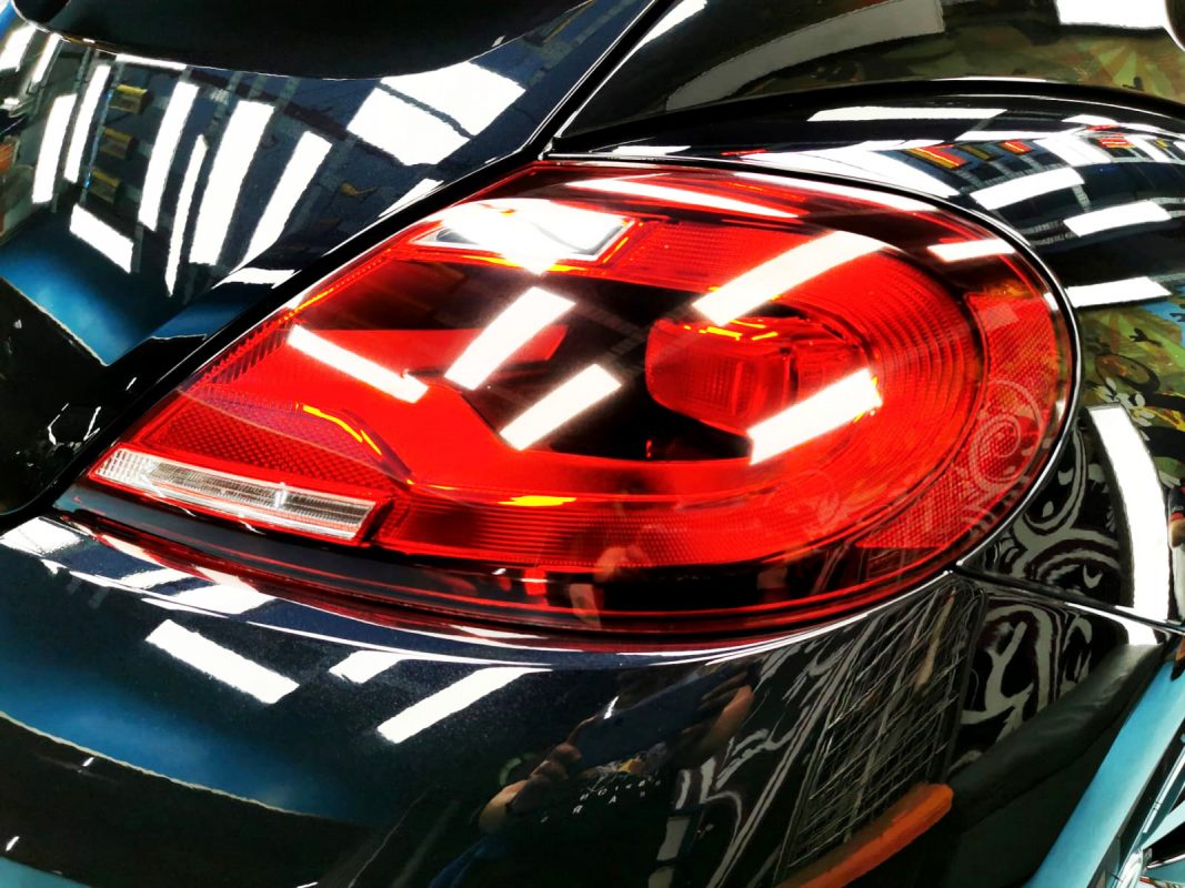 The coated bonnet of the Volkswagen Beetle under workshop lighting.