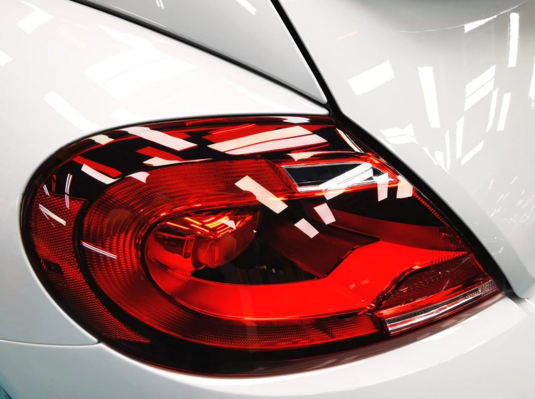 The coated bonnet of the Volkswagen Beetle under workshop lighting.