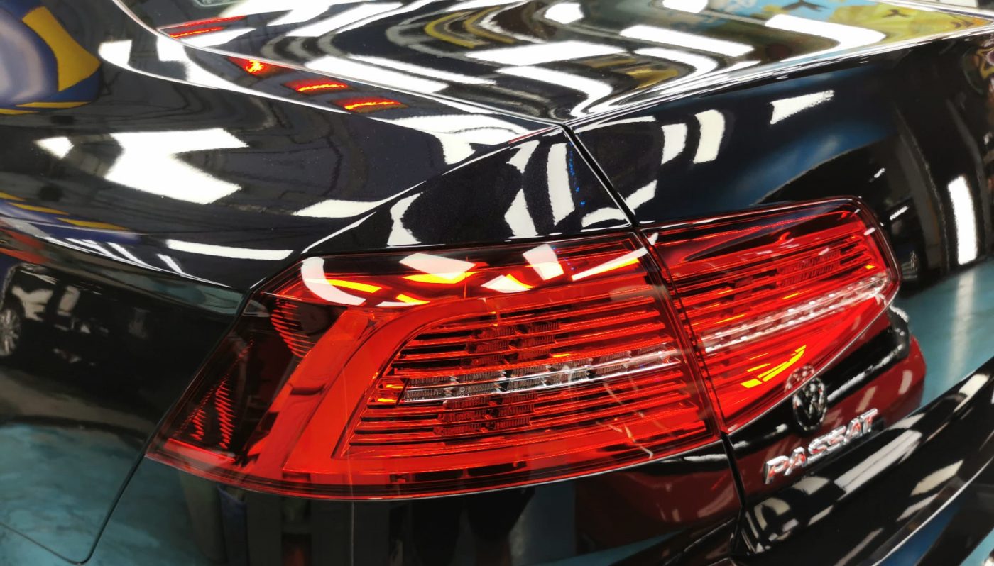 The coated bonnet of the Volkswagen Passat under workshop lighting.