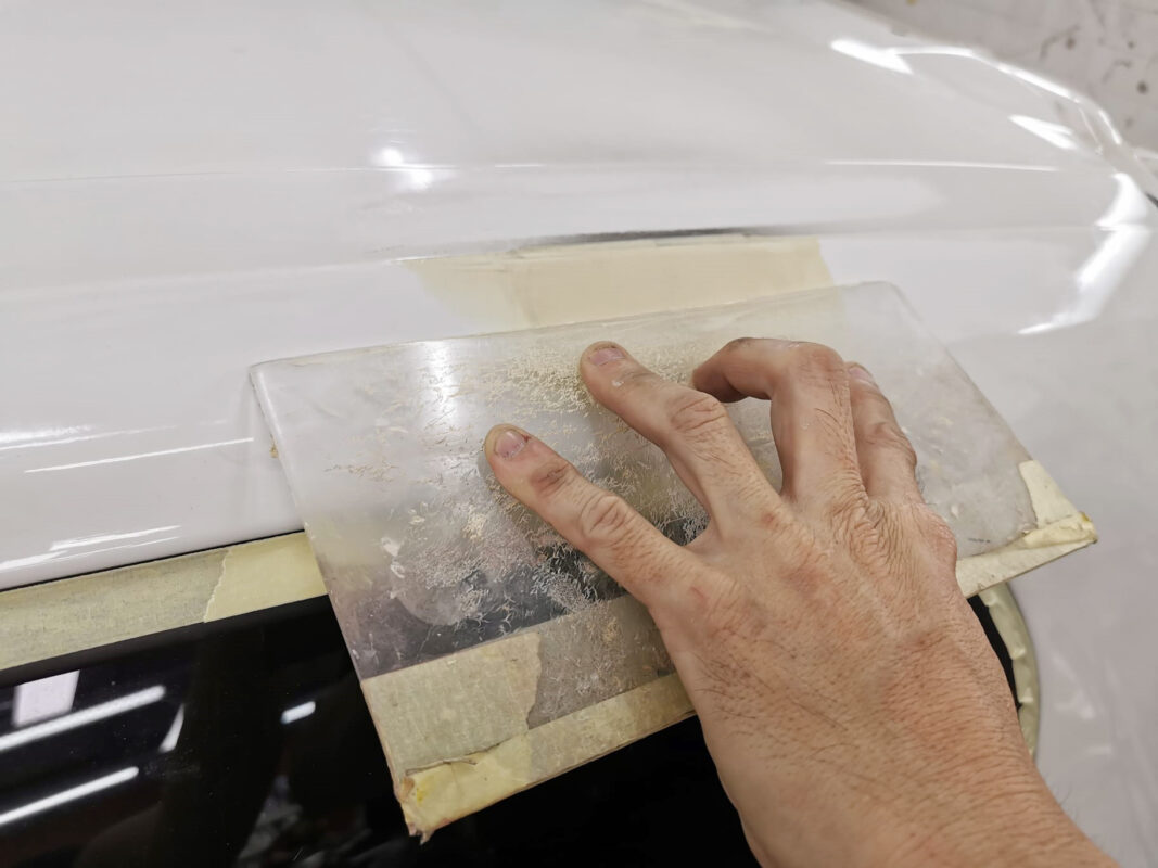 A technician wet-sanding the Scirocco's surface to level the filler.