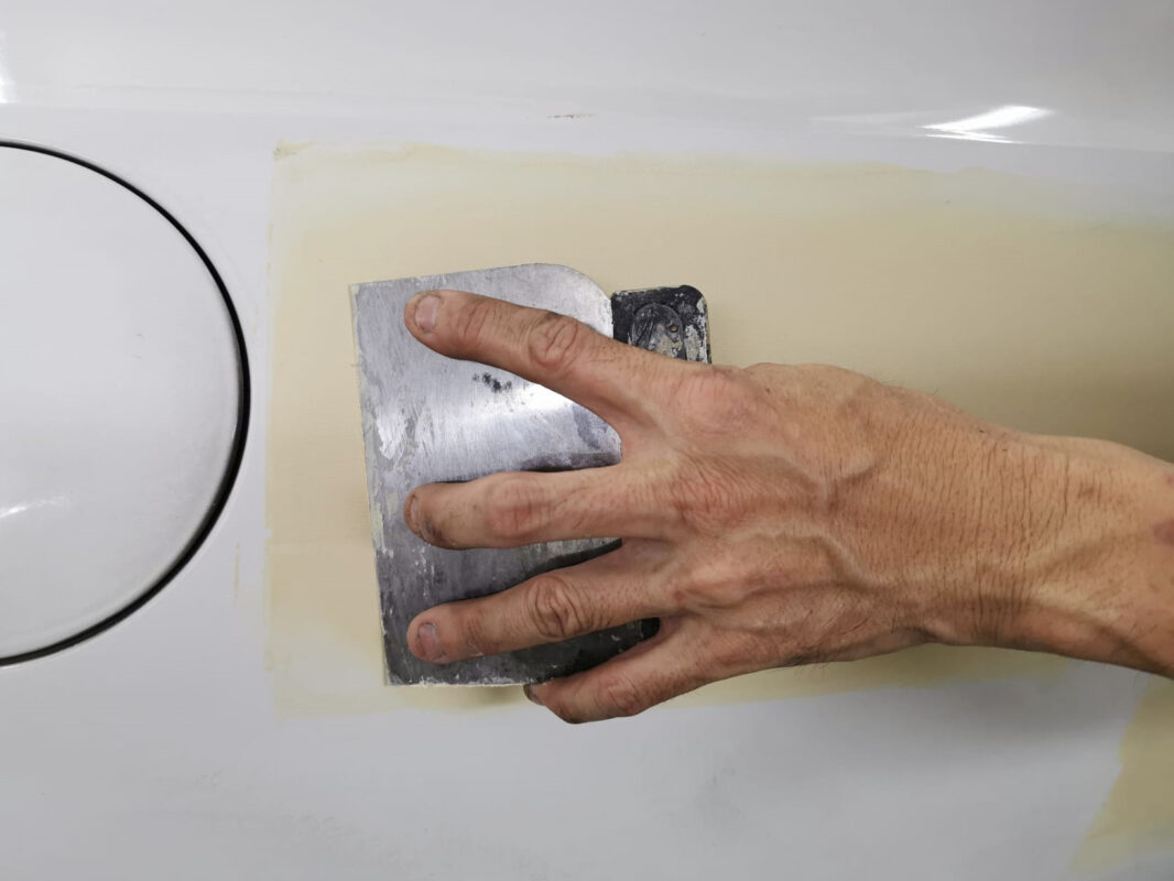 Hand-sanding a panel on the Scirocco after putty work, bringing it smooth.