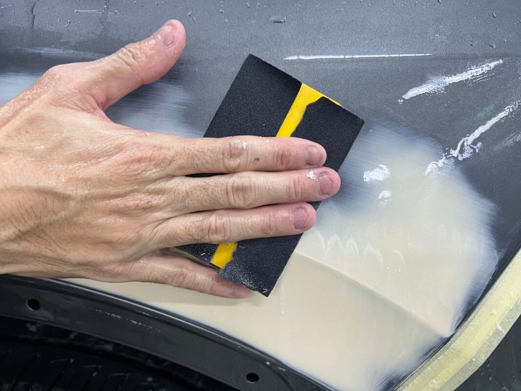 Wet-sanding the Volkswagen Tiguan's body panels to achieve a smooth surface.