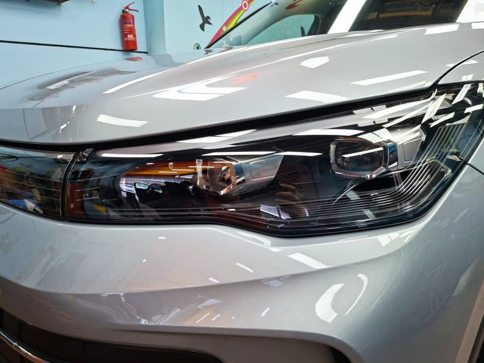 Close-up of the Tiguan LED headlight and bonnet edge with lights reflected in the paint.