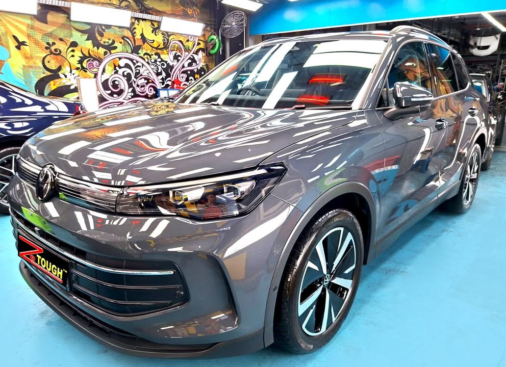 Front three-quarter view of a grey Volkswagen Tiguan in the Revol Carz Makeover studio, ZeTough plate on the front bumper.