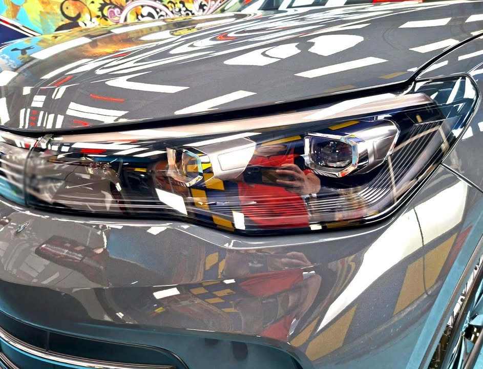 Close-up of the Volkswagen Tiguan headlight with studio lights reflected in the grey bonnet.