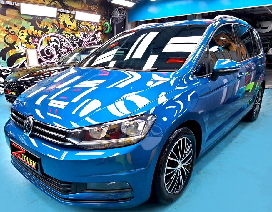 Blue Volkswagen Touran front three-quarter view in the Revol Carz workshop after ZeTough Ceramic coating.