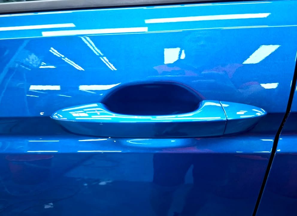 Door handle on the blue Touran door panel.