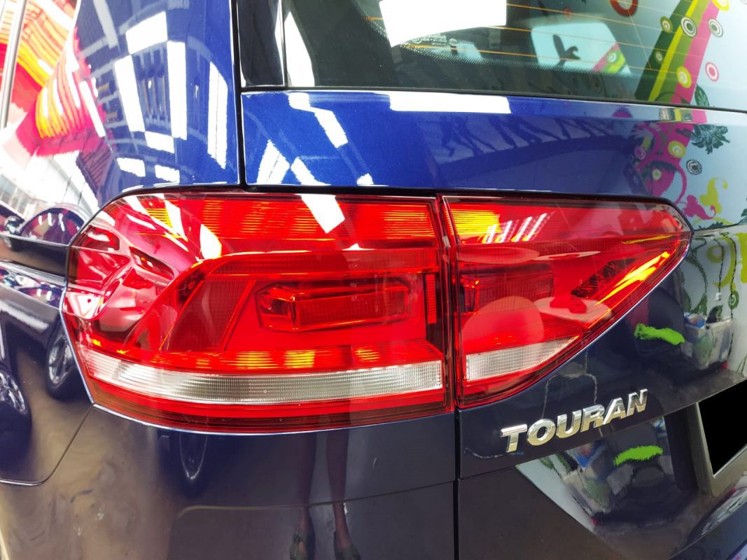 The coated bonnet of the Volkswagen Touran under workshop lighting.